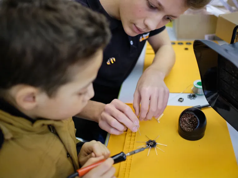 Zwei Kinder an einem Tisch mit L&ouml;tkolben